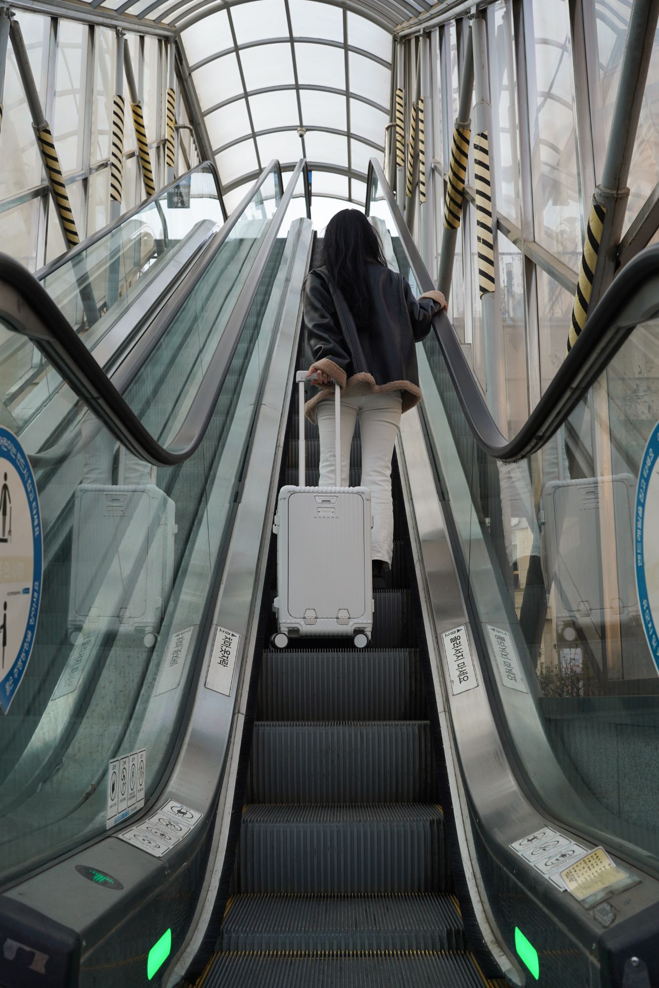 Voyageuse montant un escalator avec la Vergia Cabine en gare