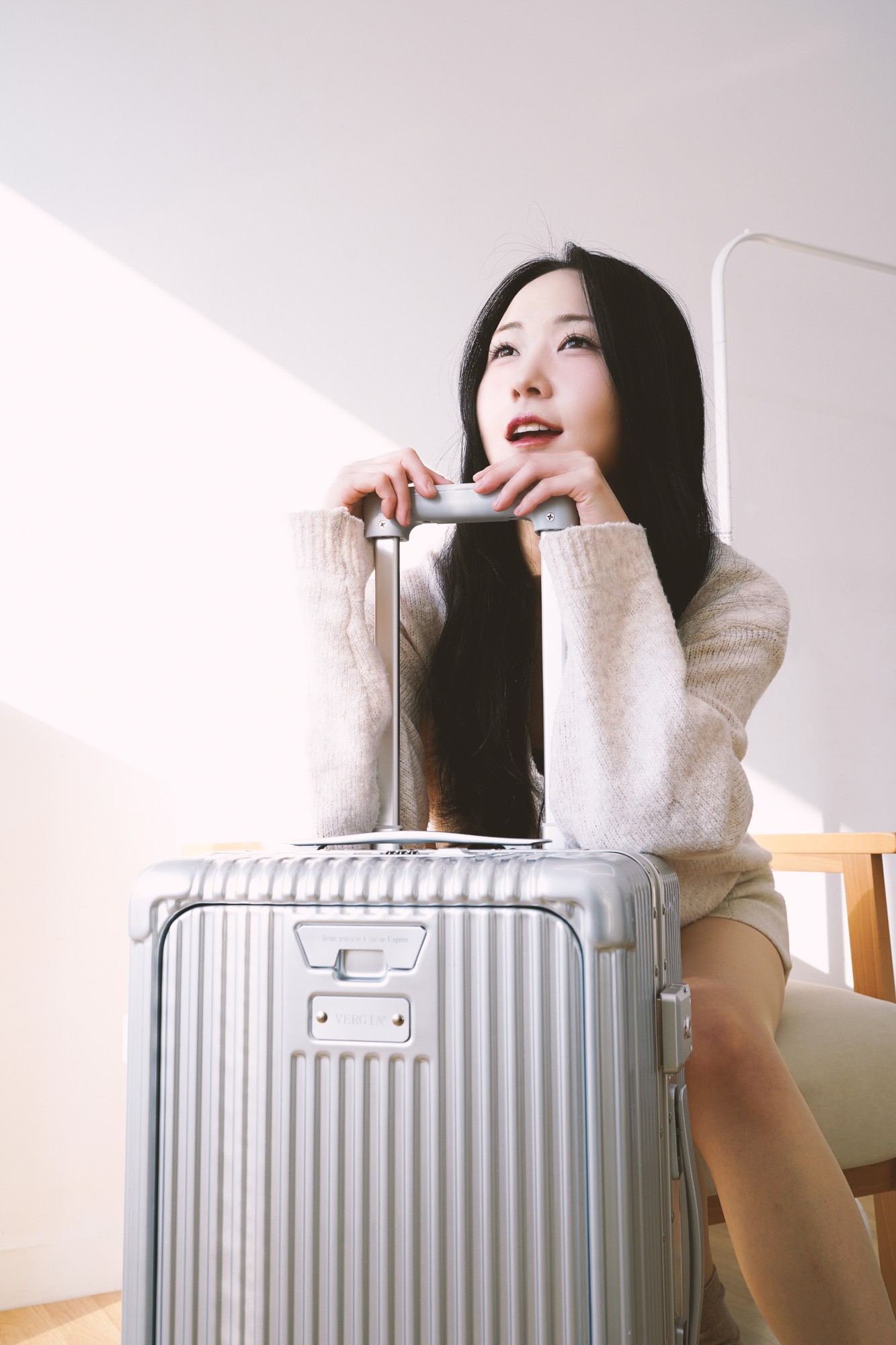 Femme tenant la valise cabine Vergia en aluminium, lumière naturelle